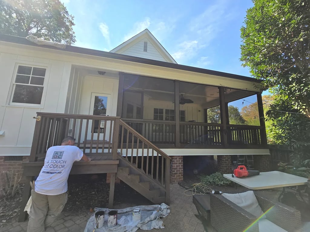 A professionally stained wood porch on Wade Avenue in Downtown Raleigh, NC. The image shows the completed project with a rich, uniform finish and a professional crew member standing on the surface, showcasing the final results of a high-durability exterior wood restoration.