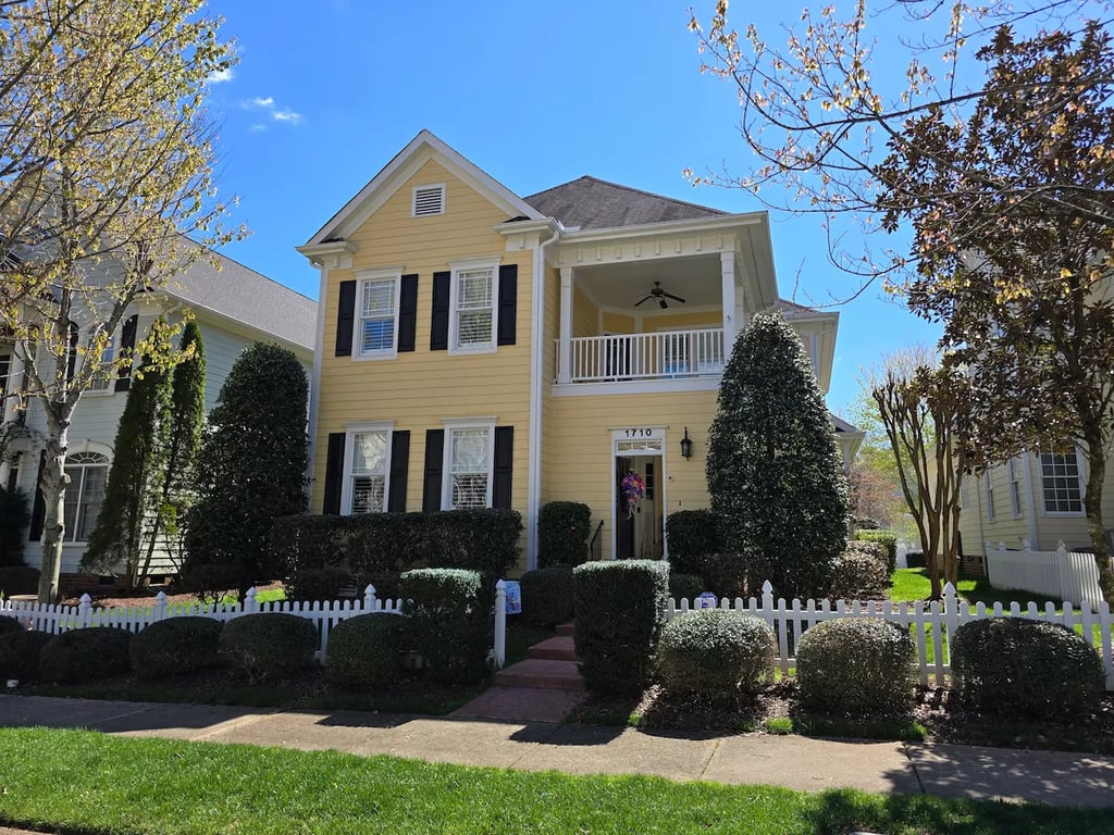 Full exterior view of a professionally painted yellow home at Happiness Hill Lane in the Bedford at Falls River neighborhood of Raleigh, NC 27614.