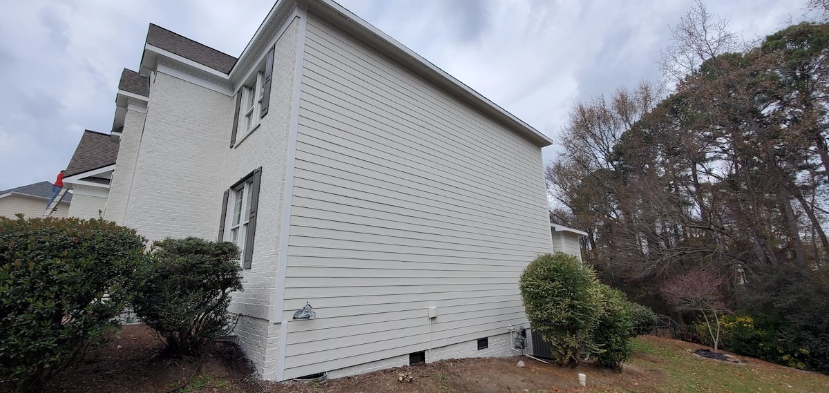 A side view of the same home with freshly painted and prepared white siding.