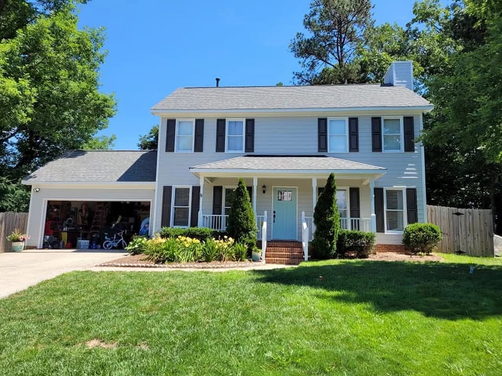 Completed exterior painting project on Laurel Branch Drive in Cary, NC, featuring modern gray siding, black shutters, and a bold blue door to showcase a professional high-performance home transformation in the Brookgreen Forest neighborhood.
