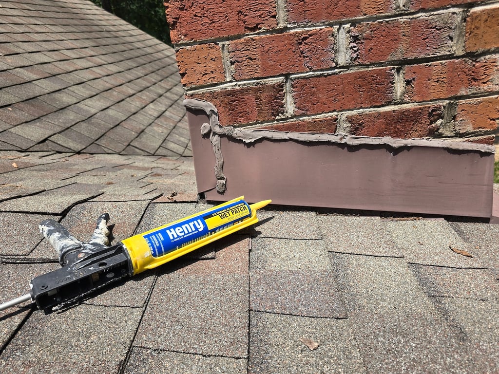 Henry water proofing Wet Patch sealant applied on chimney flashing in a brown color.