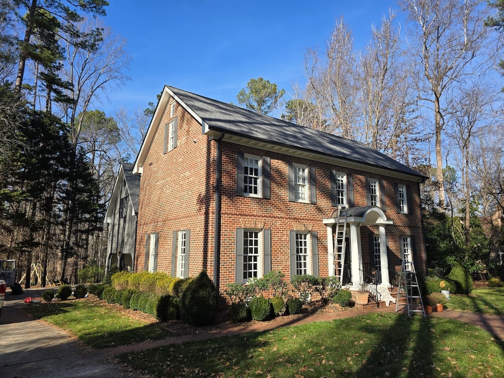 Professional painters applying Sherwin-Williams Latitude to dark architectural trim on a residential property in the Sheffield Manor neighborhood of Raleigh, NC, ensuring a durable finish against solar radiation.