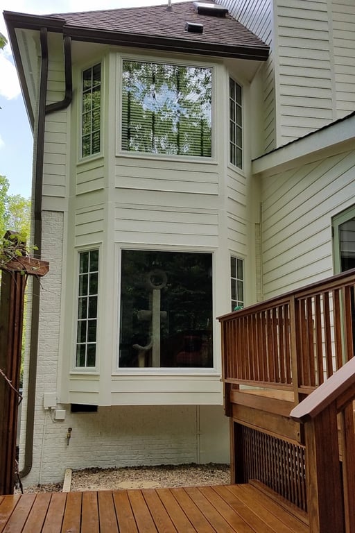 Cream colored house rear with reflection of sun on a spot free picture frame window.