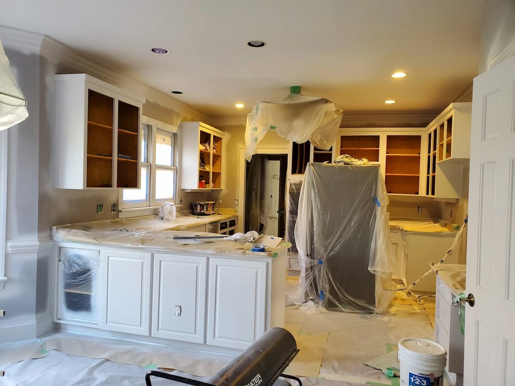 A Touch of Color Professional painters in Raleigh, NC, applying Zinsser BIN primer to kitchen cabinets to block wood tannins and ensure a high-adhesion bond during a professional cabinet refinishing project.