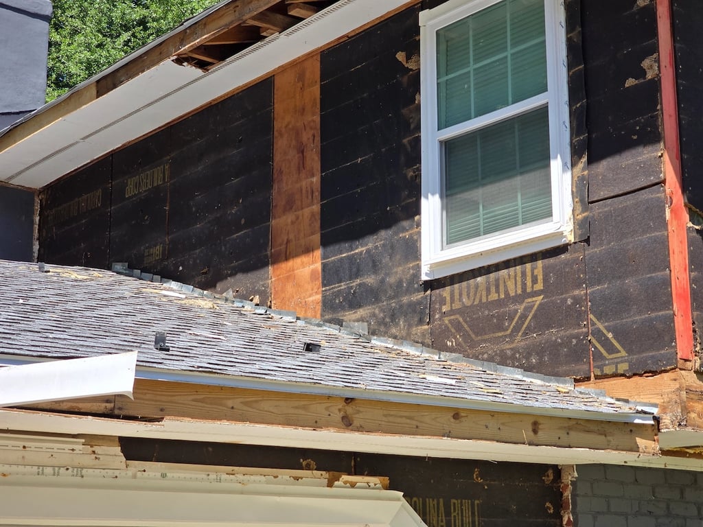 Degraded black fiber board on a home exterior after removing the siding. 