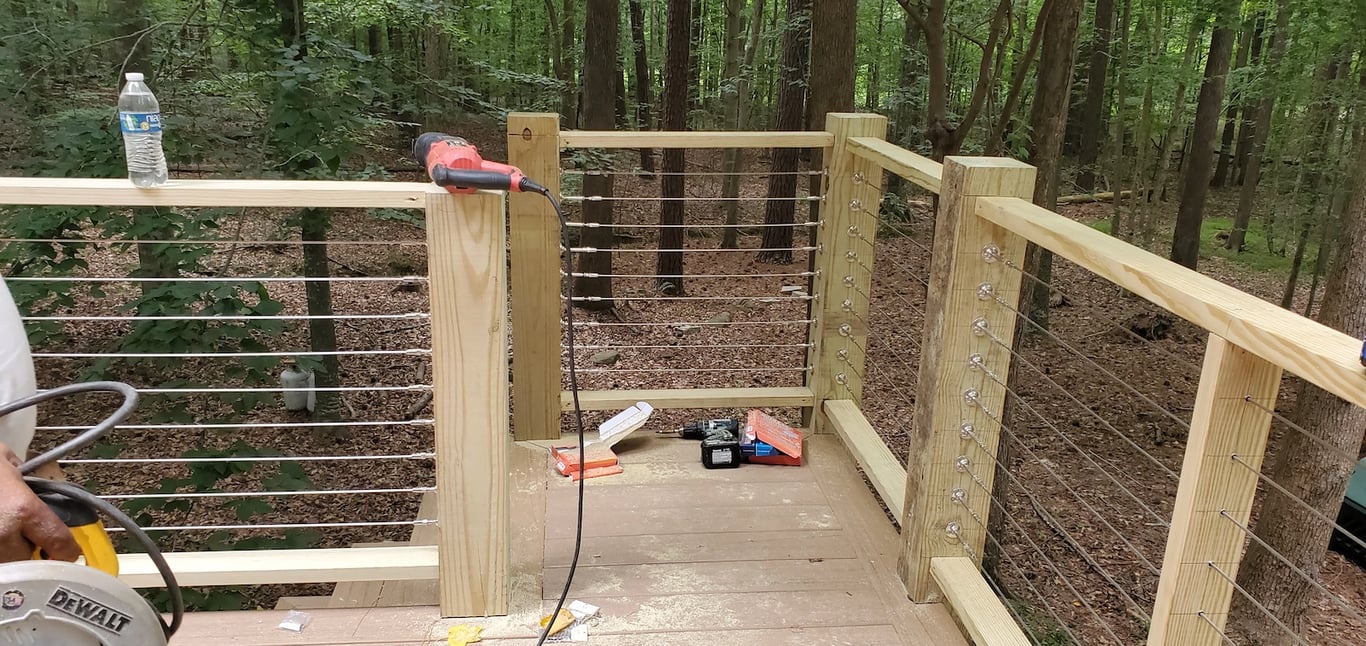 Professional deck installers in the Black Horse Run subdivision of Raleigh, NC, installing an Atlantis Stainless Steel Cable Railing system on Stallion Ct to provide a modern, low-maintenance finish that preserves scenic views.