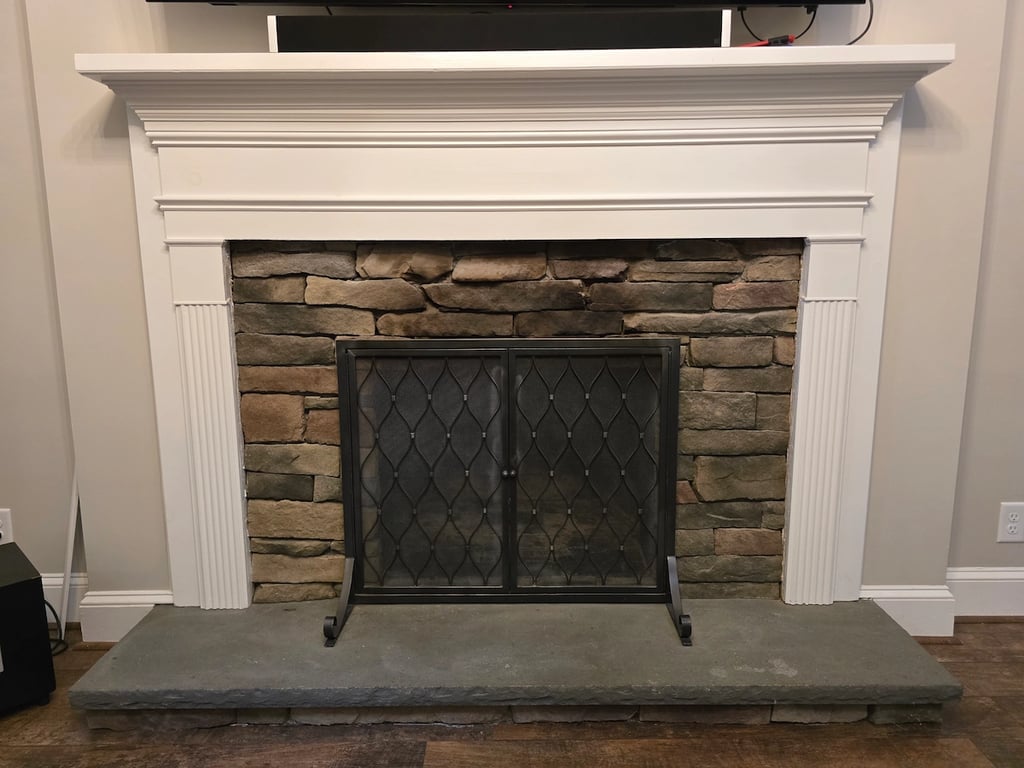 Professional assessment and cleaning of fireplace soot on stone and wood trim in a Raleigh, NC home, showcasing the technical preparation required to seal smoke stains and odors.