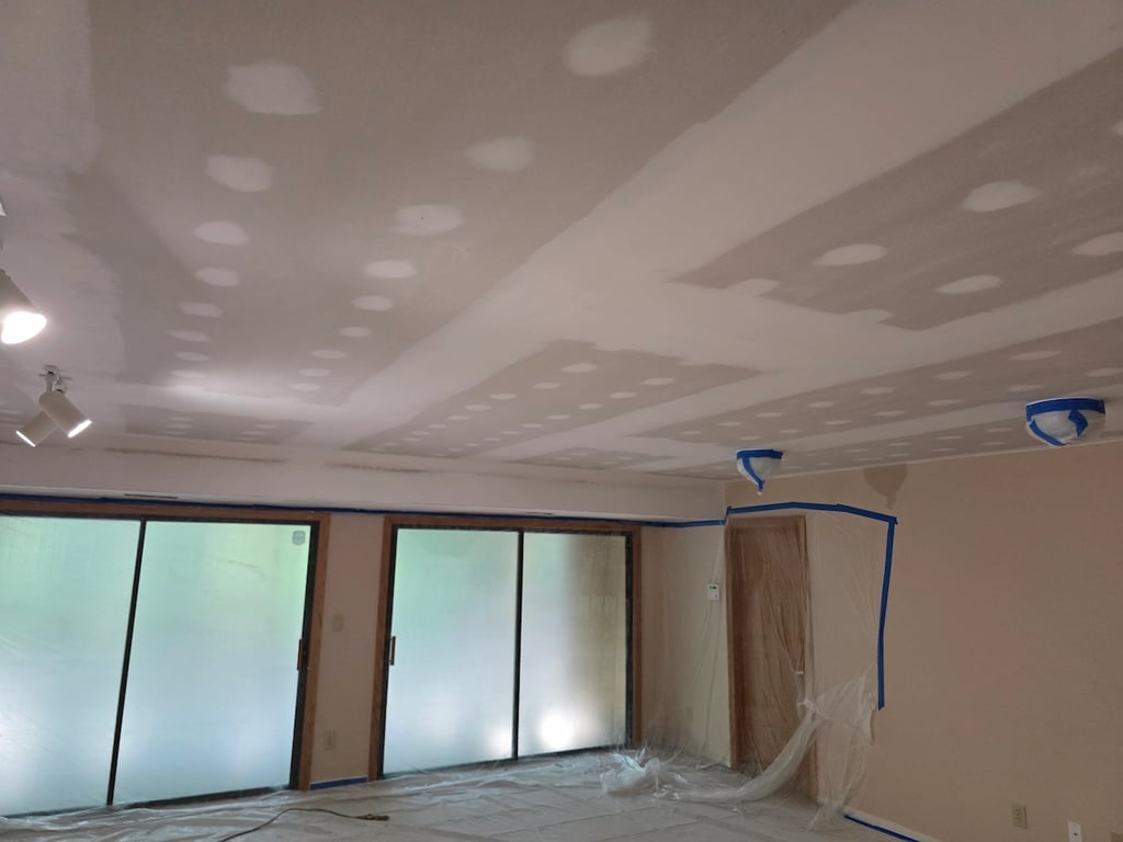 New drywall installed and seamed on a basement ceiling.
