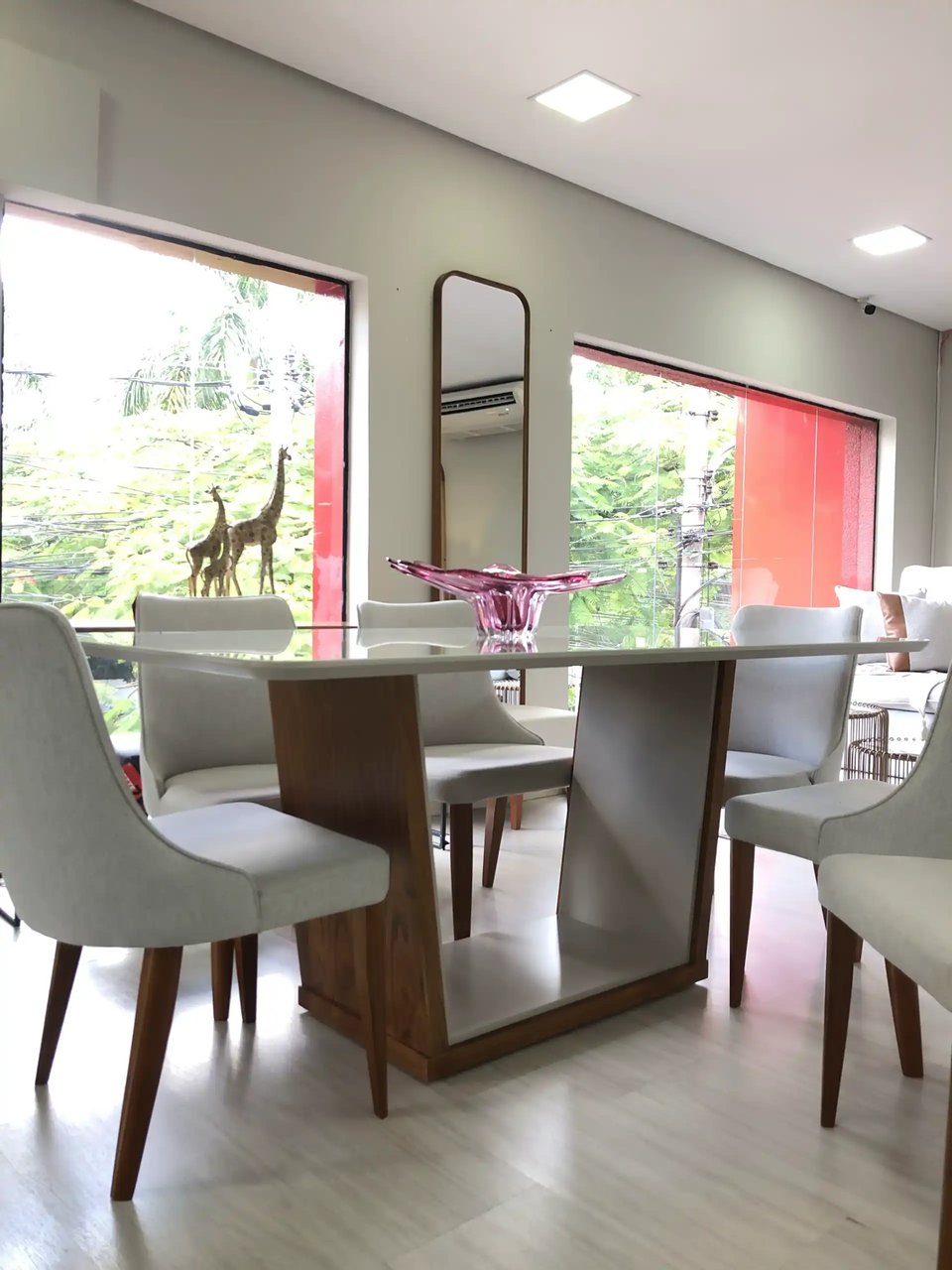 Sala de estar com iluminação em camadas — pendente, spots e abajur combinados com sofá e poltrona