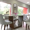 Sala de estar com iluminação em camadas — pendente, spots e abajur combinados com sofá e poltrona