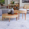 Sala de estar ampla com sofá, mesa de centro e poltrona fotografados em perspectiva, luz natural lateral