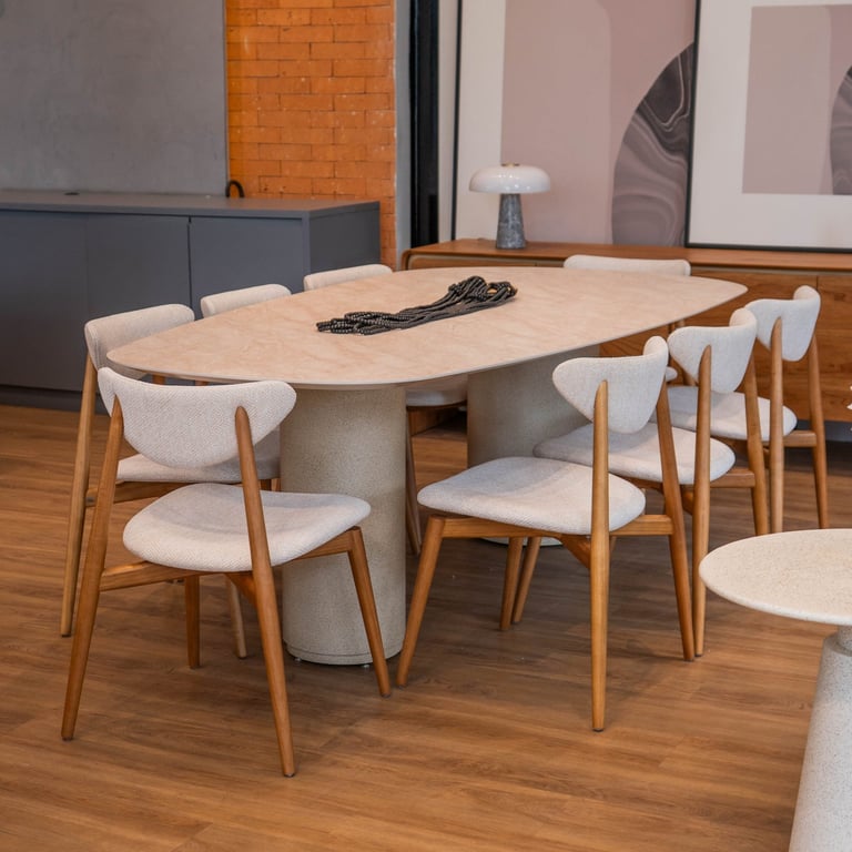 Mesa de jantar Cedro com tampo orgânico cor areia sobre base de duplo pilar cilíndrico, com cadeiras de madeira