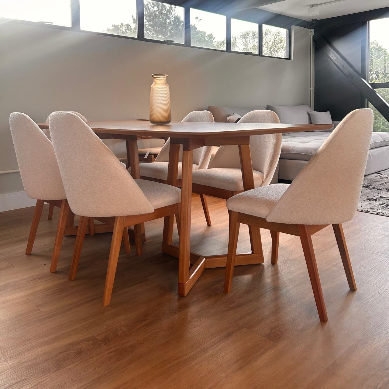 Mesa de jantar Lua com tampo em madeira e base escultural de pernas cruzadas em cinamomo, com seis cadeiras estofadas em bouclé off-white