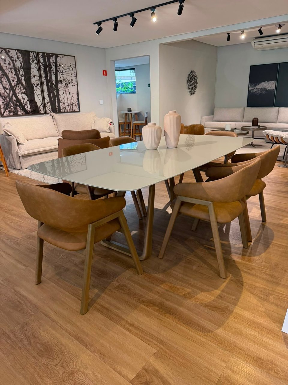 Mesa de jantar Zoe com pés em madeira maciça e cadeiras estofadas formato poltrona, vista em perspectiva