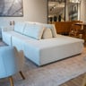 Sofá Ilha em tecido off-white, formato de ilha sem braços, com almofadas soltas de encosto, sobre tapete em showroom
