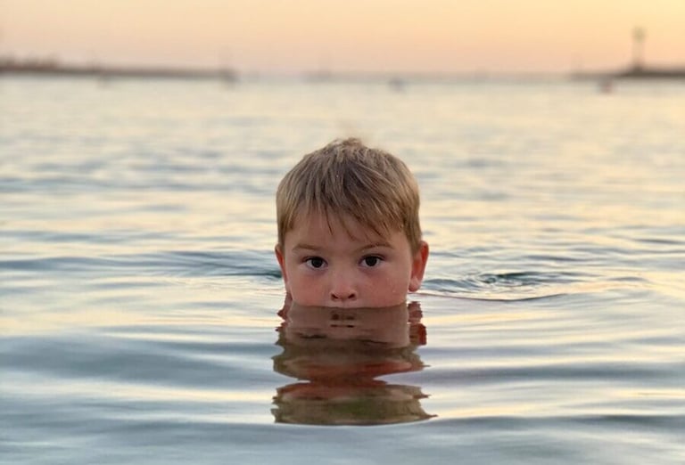 boy in body of water during daytime
