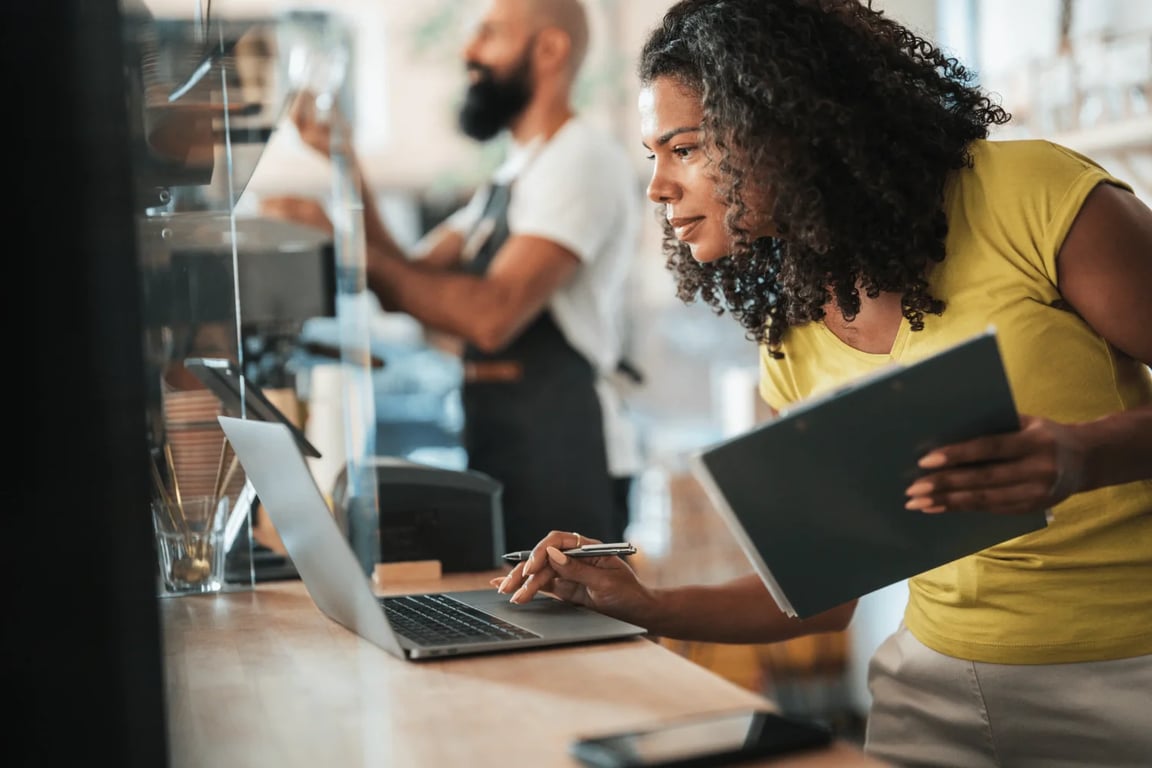 Geschäftsinhaberin arbeitet am Laptop an der Theke