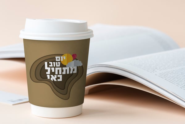 Takeaway coffee cup mockup on a table with an open book