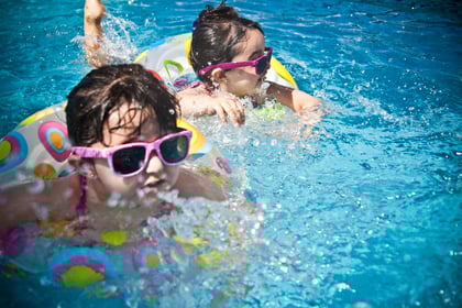 Picture of two young girls swimming in a pool with their floatation rings