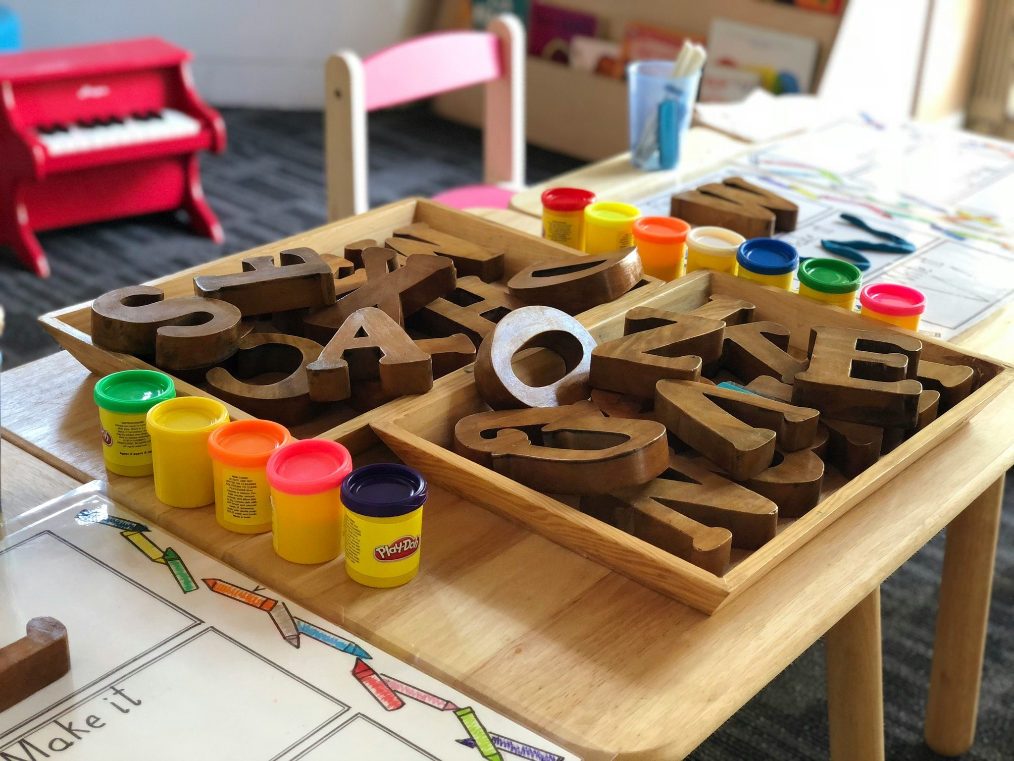 Wooden letter blocks and PlayDoh on a table.