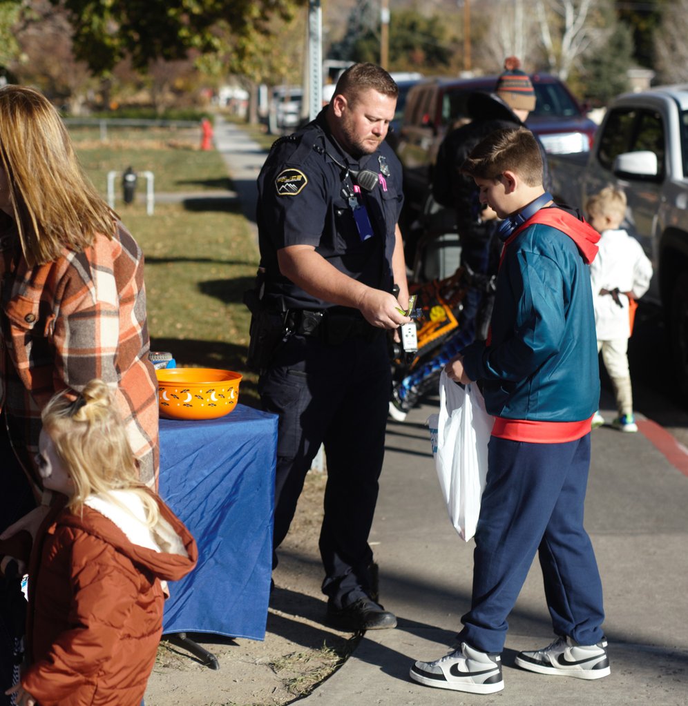 A police officer hands candy to a child during a Halloween event.