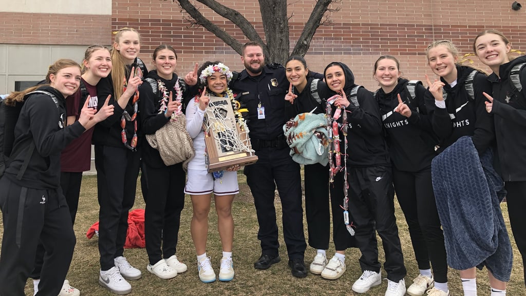 A police officer poses with the high school women's basketball team.