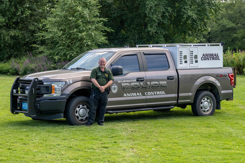 The animal control officer stands next to the ACO truck.