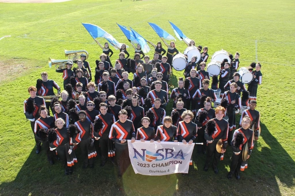 Marching band holding 2024 NESBA championship for division 4 banner