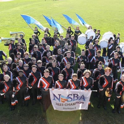 Marching band holding 2024 NESBA championship for division 4 banner