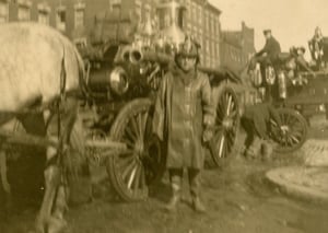Hoseman John L. Glynn beside Engine 3's steam pumper, on Harrison Av., corner of Bristol St., South End, circa 1911.