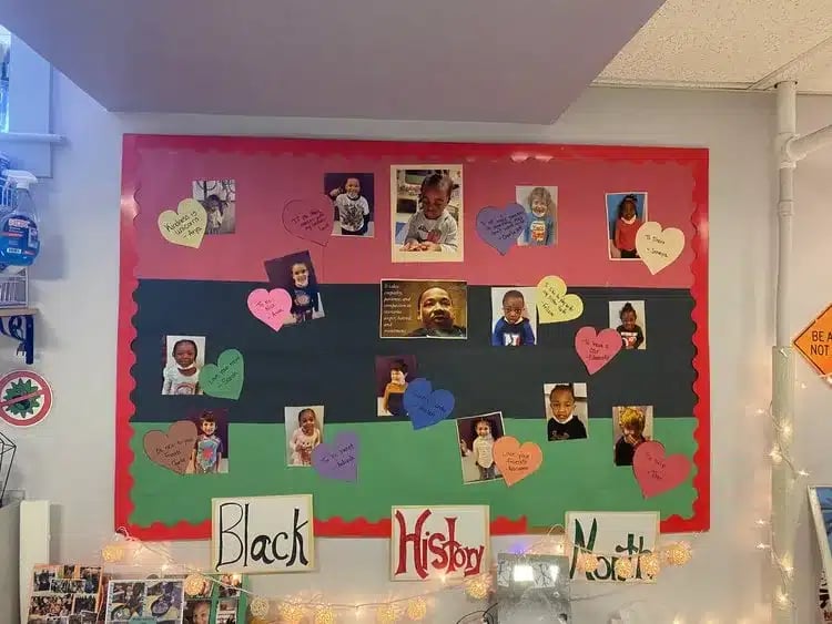 A preschool classroom bulletin board decorated in red, black, and green for Black History Month.