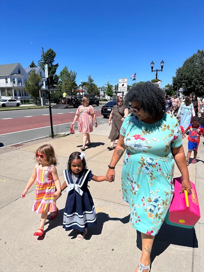 A group of preschool graduates stand in front of the Elizabeth Peabody House with their graduation caps.