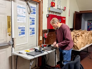 Thomas sets up a table with two laptops for guest registration during the food pantry's Thanksgiving distribution.