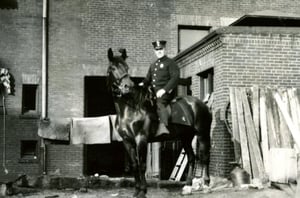 Ladderman Gilbert W. Jones riding a police horse at the rear of quarters, 941 Boylston Street, Back Bay, circa 1920.