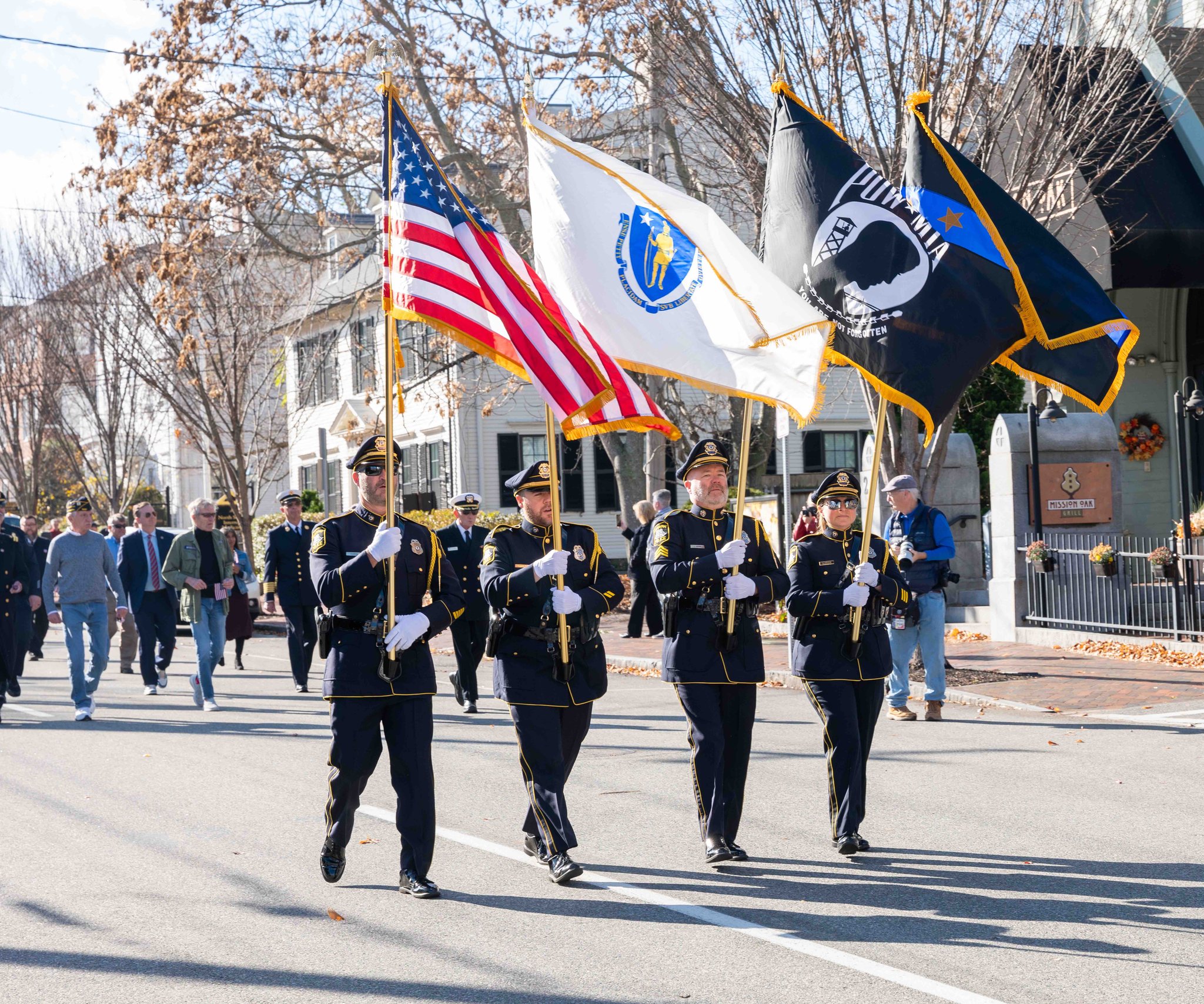 Four honor guard members carrying flags at a Veterans Day Event.