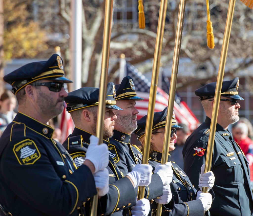 Four honor guard members carrying flags at a Veterans Day Event.