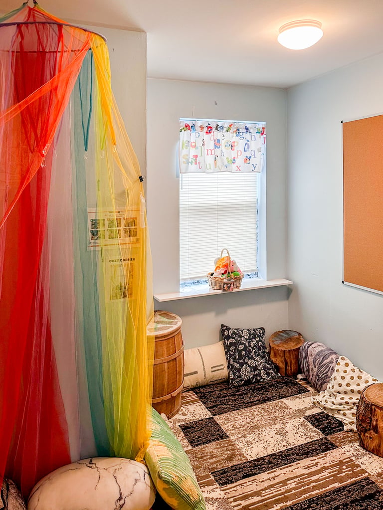 A room with blue walls, plush carpets, cozy pillows, and a tent-like set of multicolor curtains creating a semi-secluded corner nook.