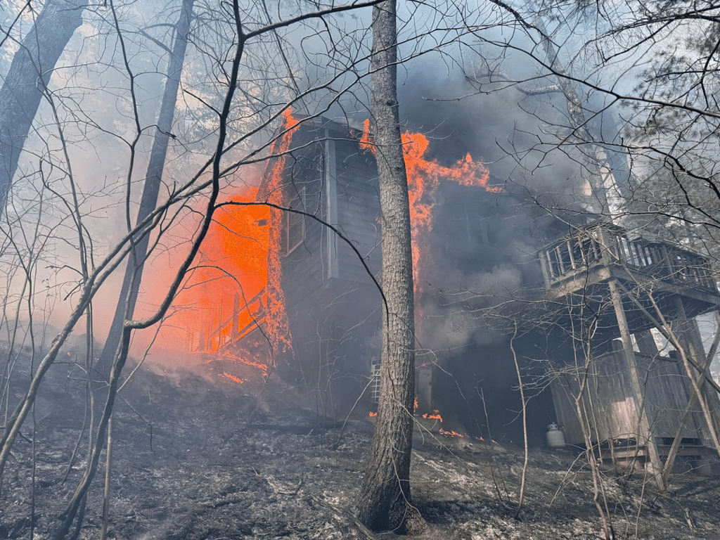 A significant brush fire spread to an unoccupied, seasonal log cabin in the area of Lowell and Old Dunstable roads on Tuesday afternoon. Firefighters from Groton and several mutual aid communities were eventually able to extinguish the fire. (Photo Courtesy Groton Fire Department)