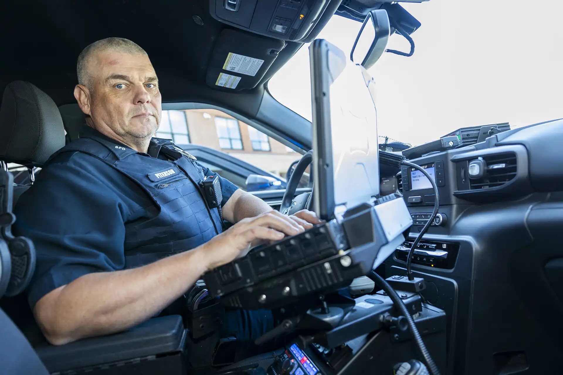 A male Billerica Police officer sits in a police cruiser.