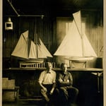 Captain John F. Williams, left, in quarters of Engine 44, with models sailboats made by firefighters, circa 1929.