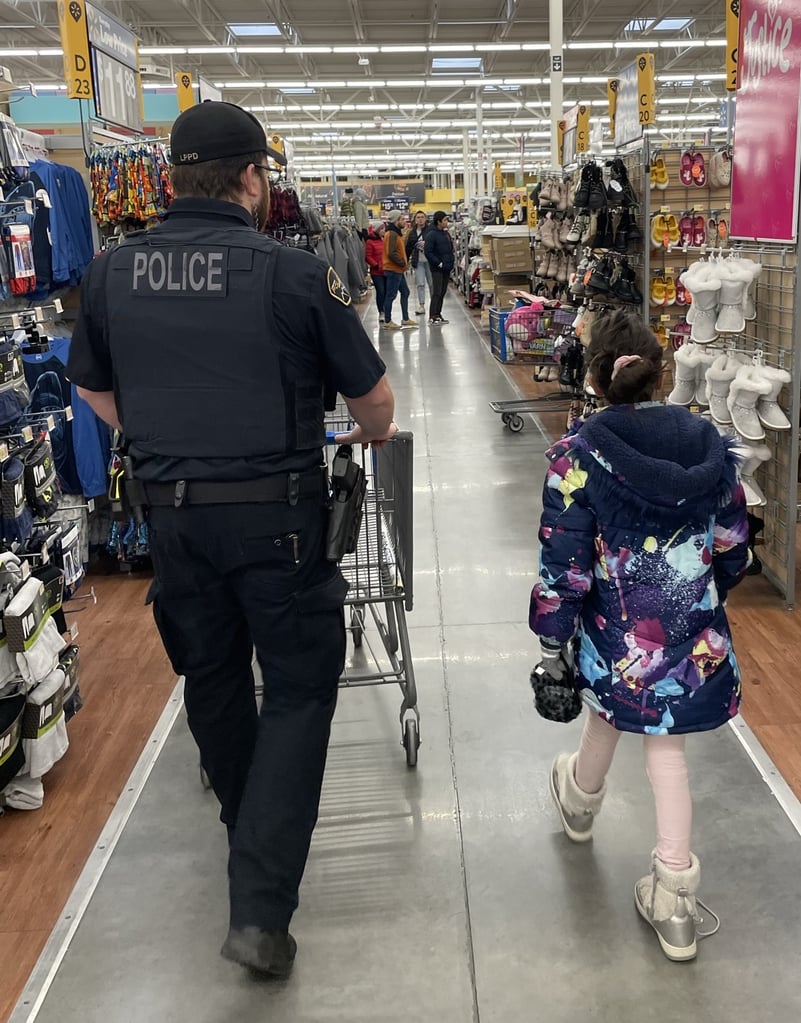 A police officer walks through a department store with a young community member