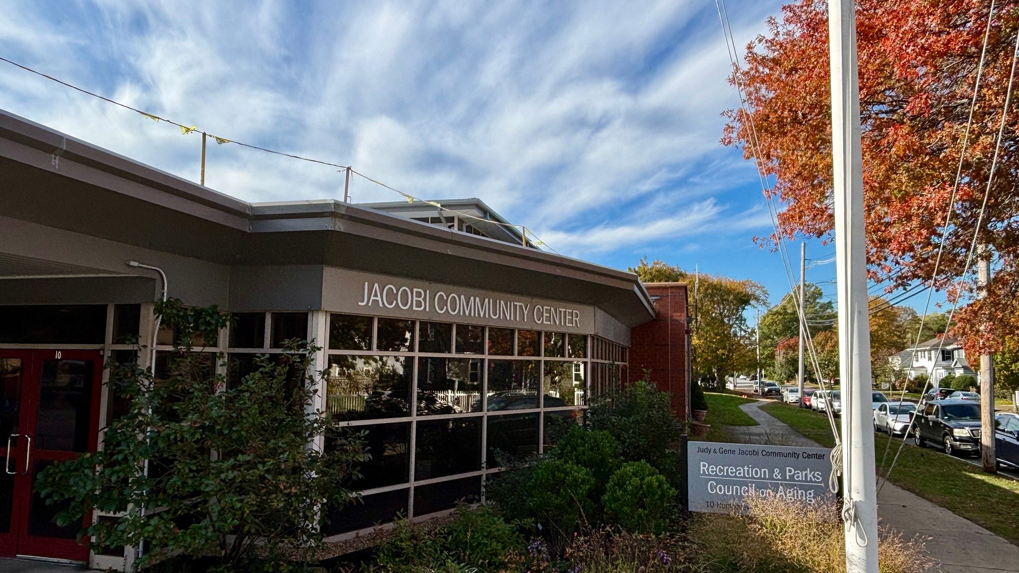 Front of Judy and Gene Jacobi Community Center with construction flags on roof.