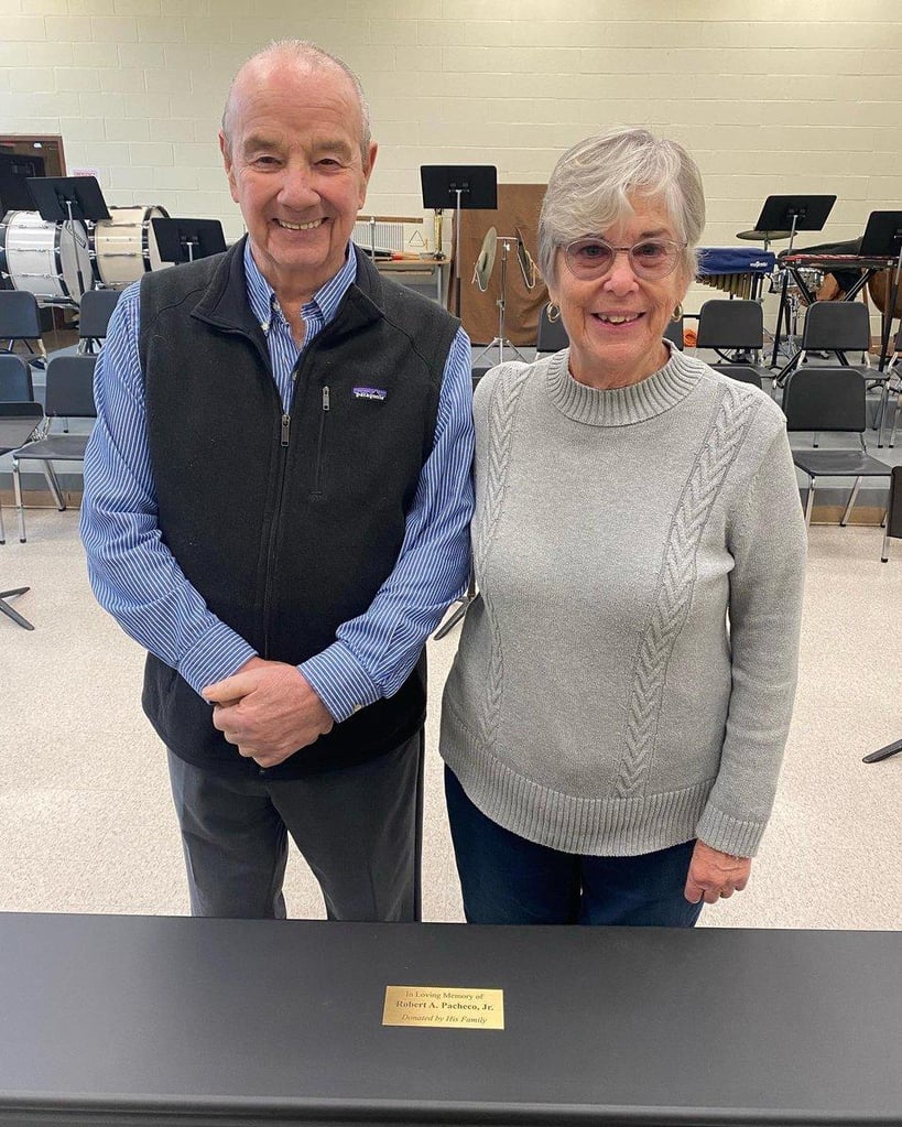 Bob and Barbara Pacheco, the parents of late Bourne High School teacher Robert A. Pacheco Jr., stand in front of the digital piano they donated to the high school's music department. (Photo courtesy Bourne Public Schools)