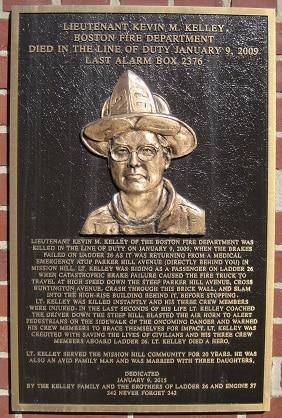 Memorial plaque mounted on the brick wall on Huntington Av., opposite Parker Hill Ave.