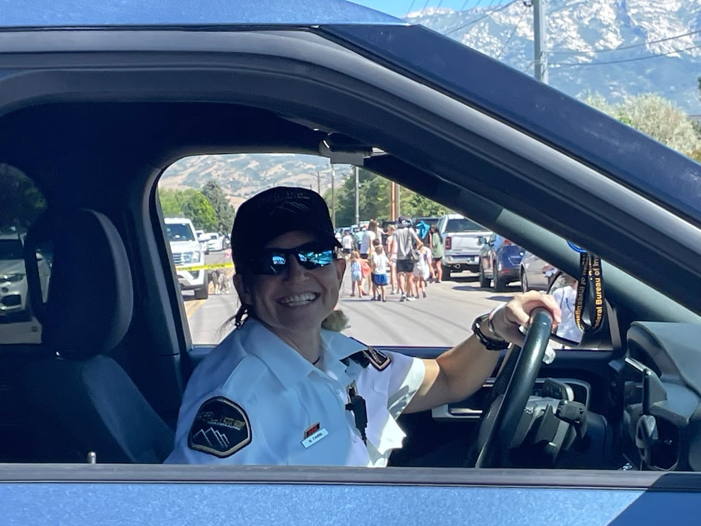 A female police officer smiles while sitting in a police cruiser.