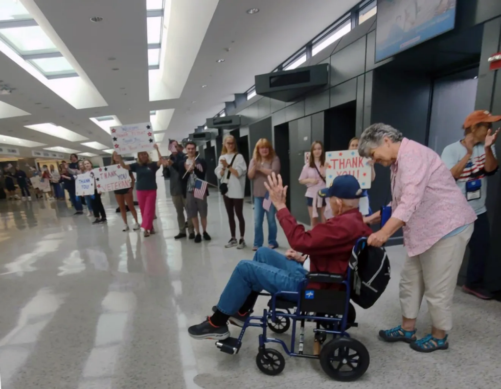 World War II veteran and retired Billerica Police Capt. Paul Holmes is greeted as he is led into Dulles International Airport by his daughter Judy Holmes.