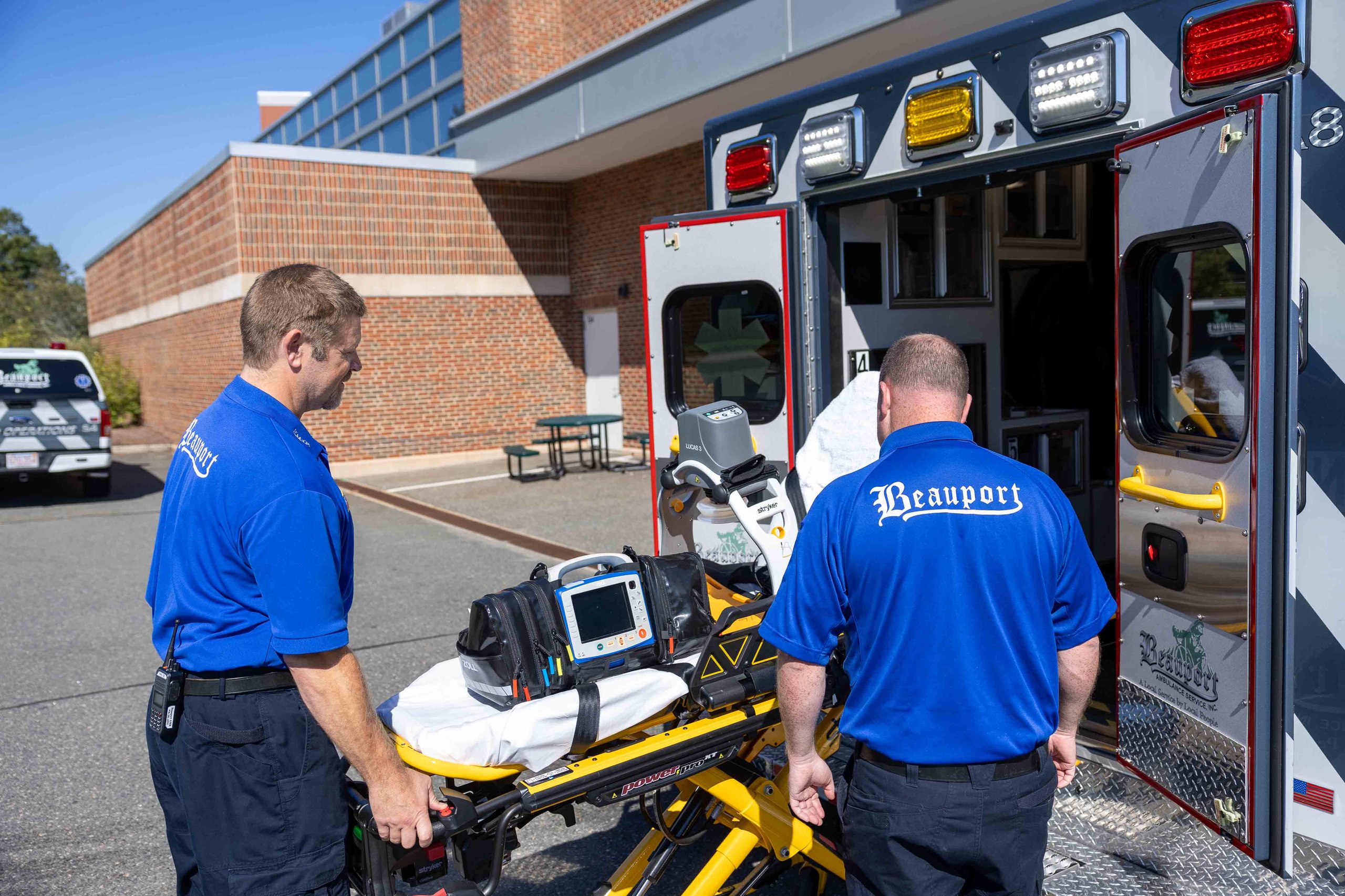 Two workers loading a gurney on an ambulance.