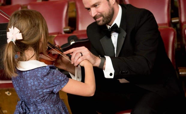 Melrose Schools Orchestra Director Luke Miller, seen here assisting a young student with the violin, has been named the state's Orchestra Director of the Year. (Courtesy Photo/Melrose Symphony Orchestra)