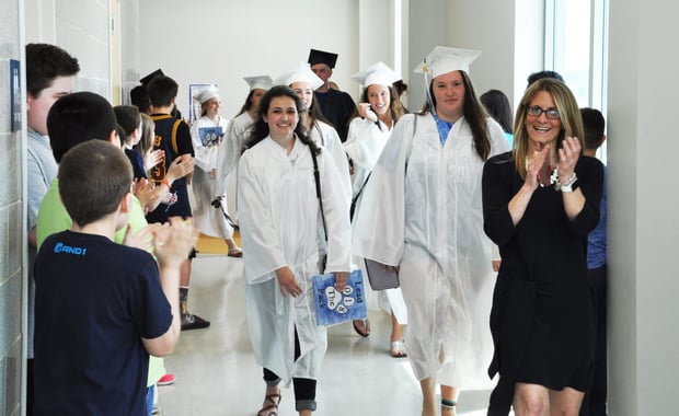 Rockland High School Seniors Macie Jones (middle-left holding blue folder) and Emily McLaughlin walk the halls of the Rogers Middle School 5th grade hallway as Assistant Principal Cheryl Schipper applauds. (Courtesy Photo)