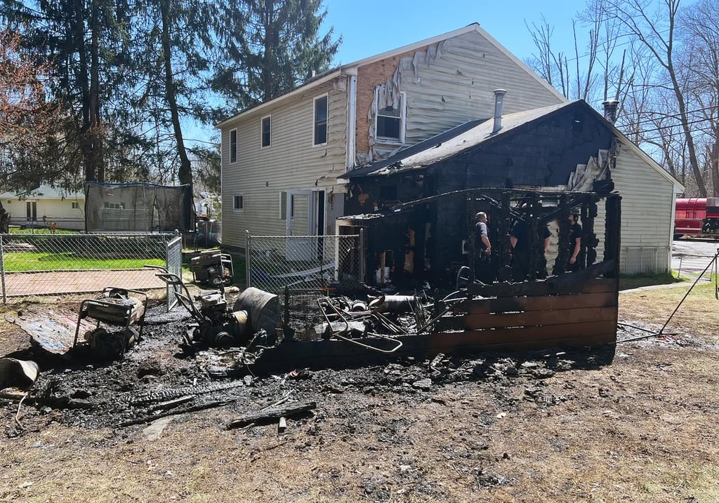 Burned out barn, adjacent home with melted siding and heavy fire damage
